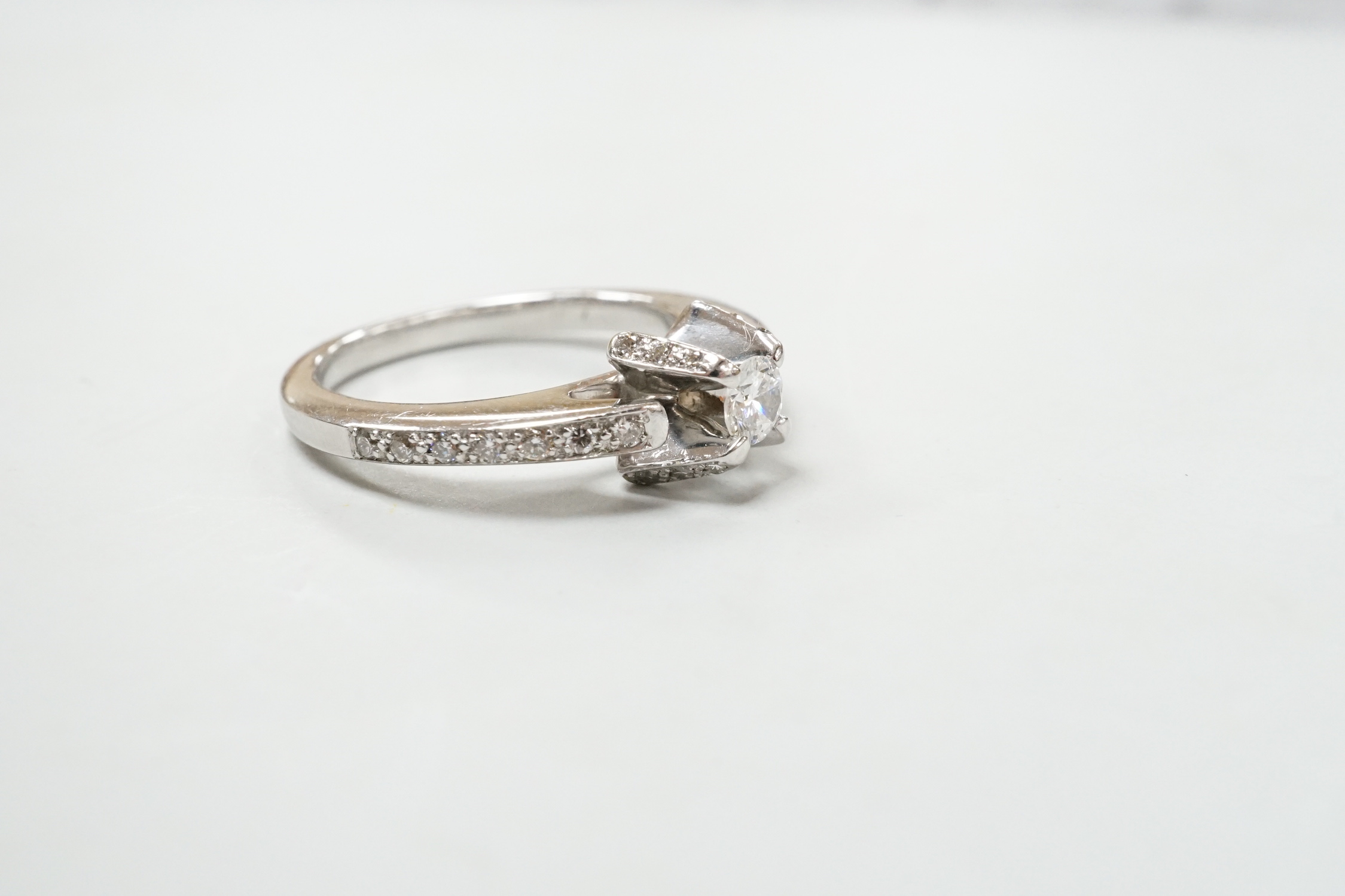 A modern 18ct white gold and claw set single stone diamond ring, with diamond chip set shoulders, size M, gross weight 5.2 grams.